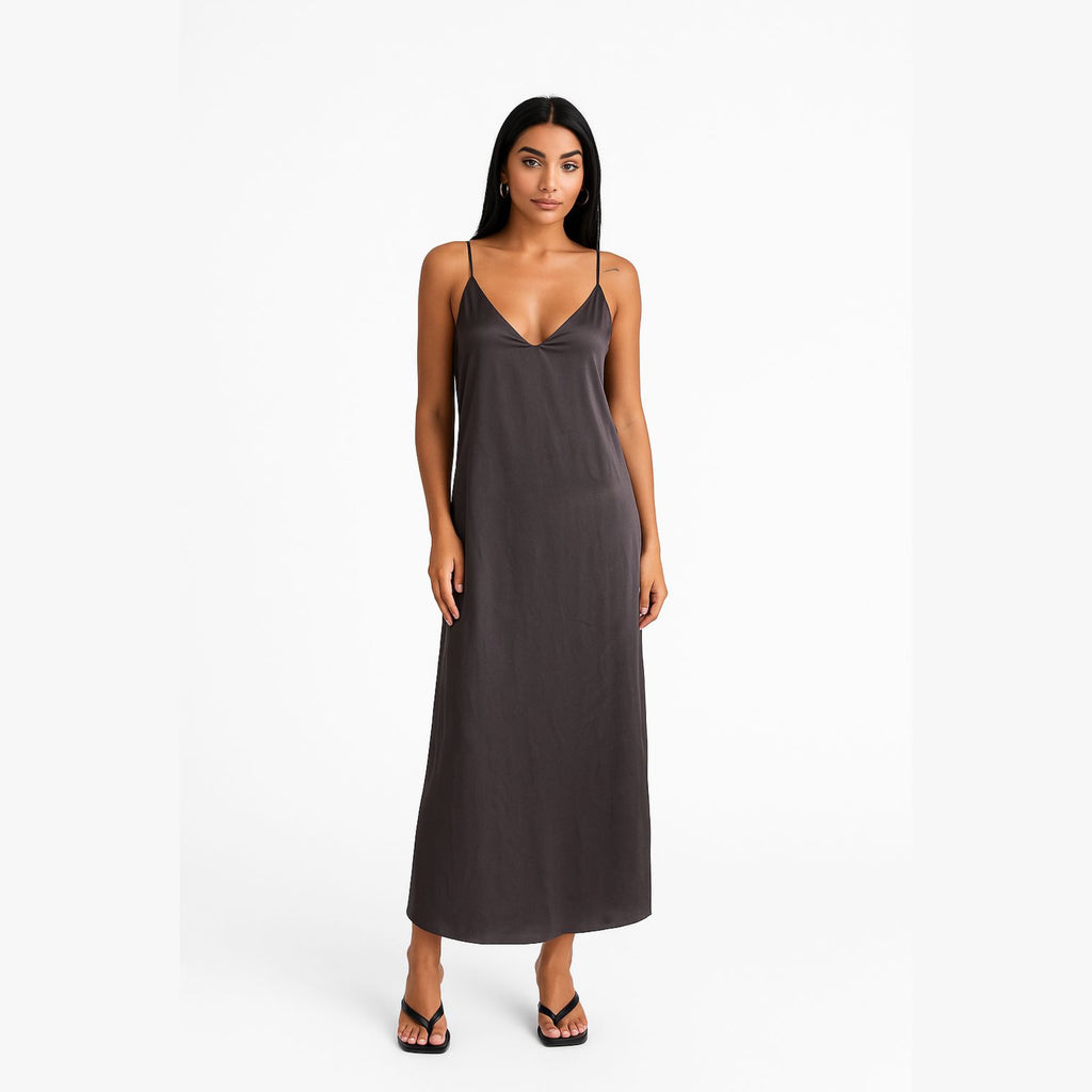 Woman wearing a long dark gray slip dress on a white background