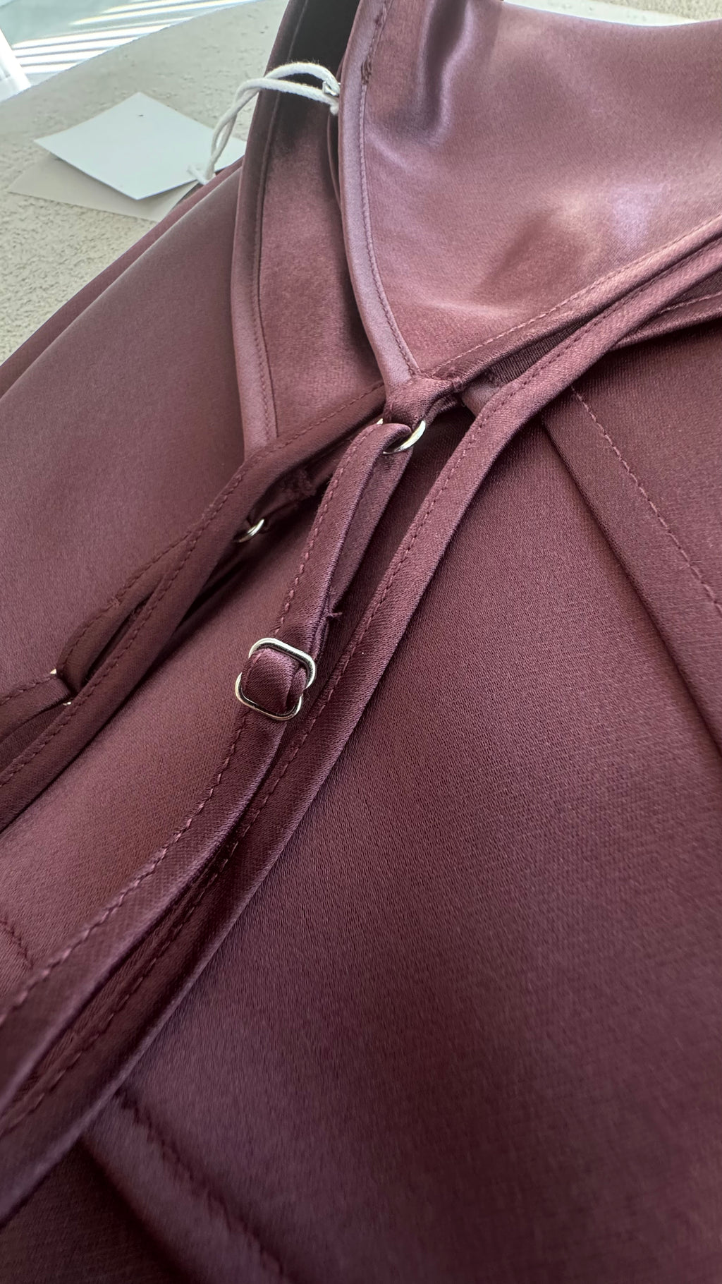 Close-up of a maroon leather bag with a buckle detail.
