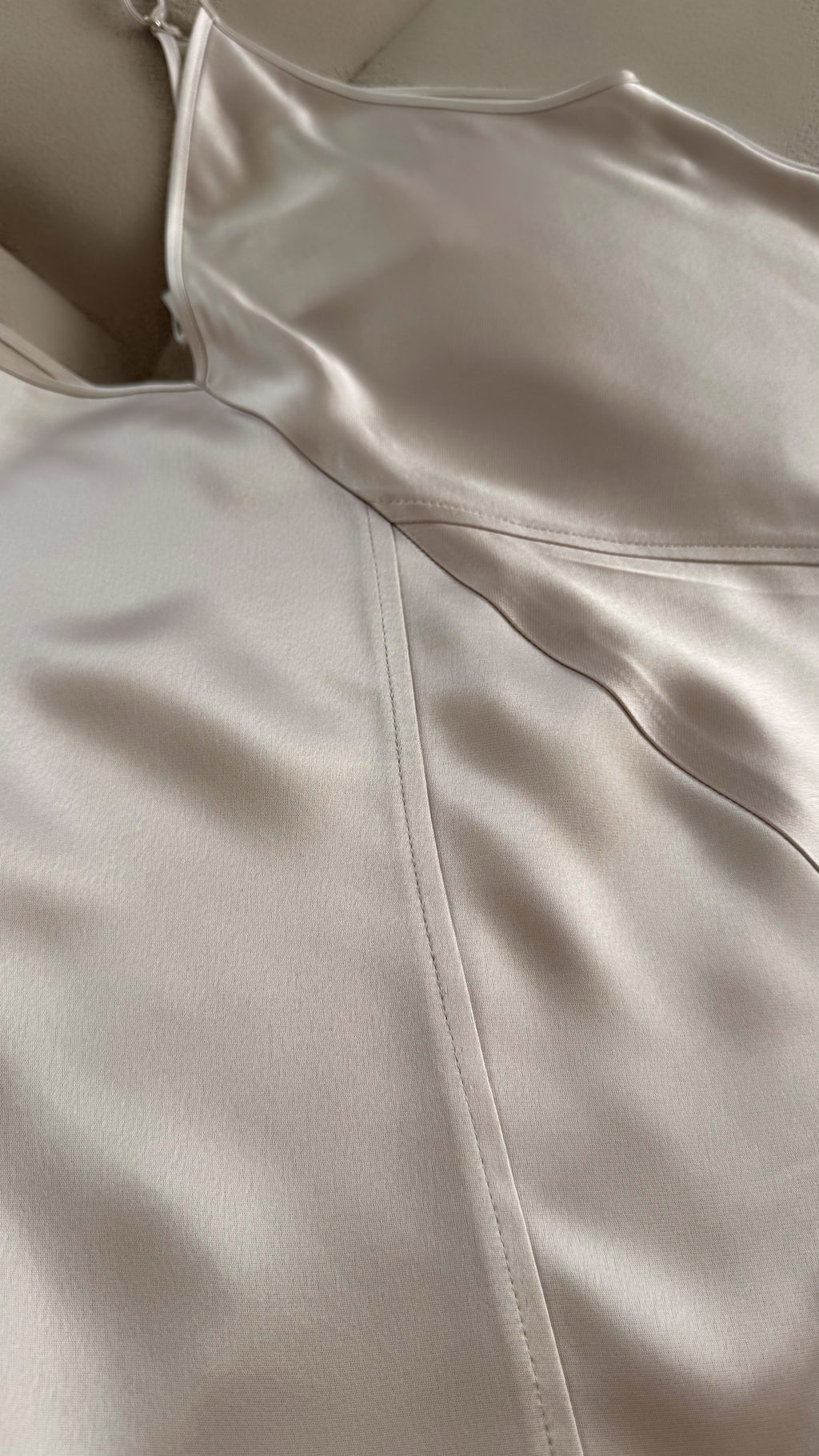 Close-up of a beige dress with a zipper detail on a plain background
