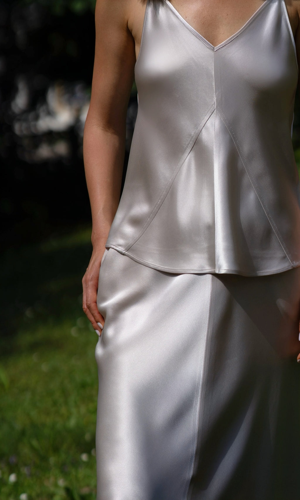 Person wearing a silver satin outfit with a blurred background
